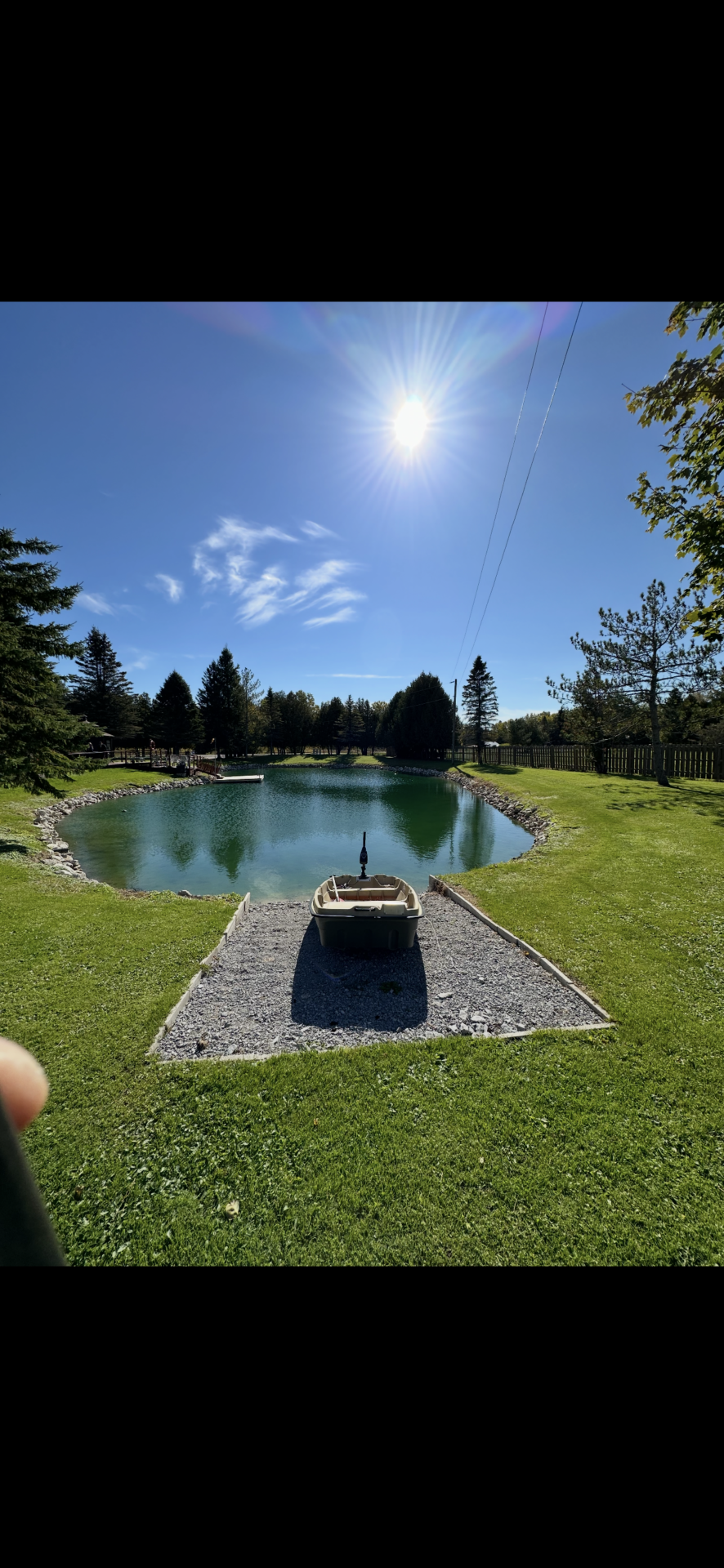 The sun shines down over a well manicured pond